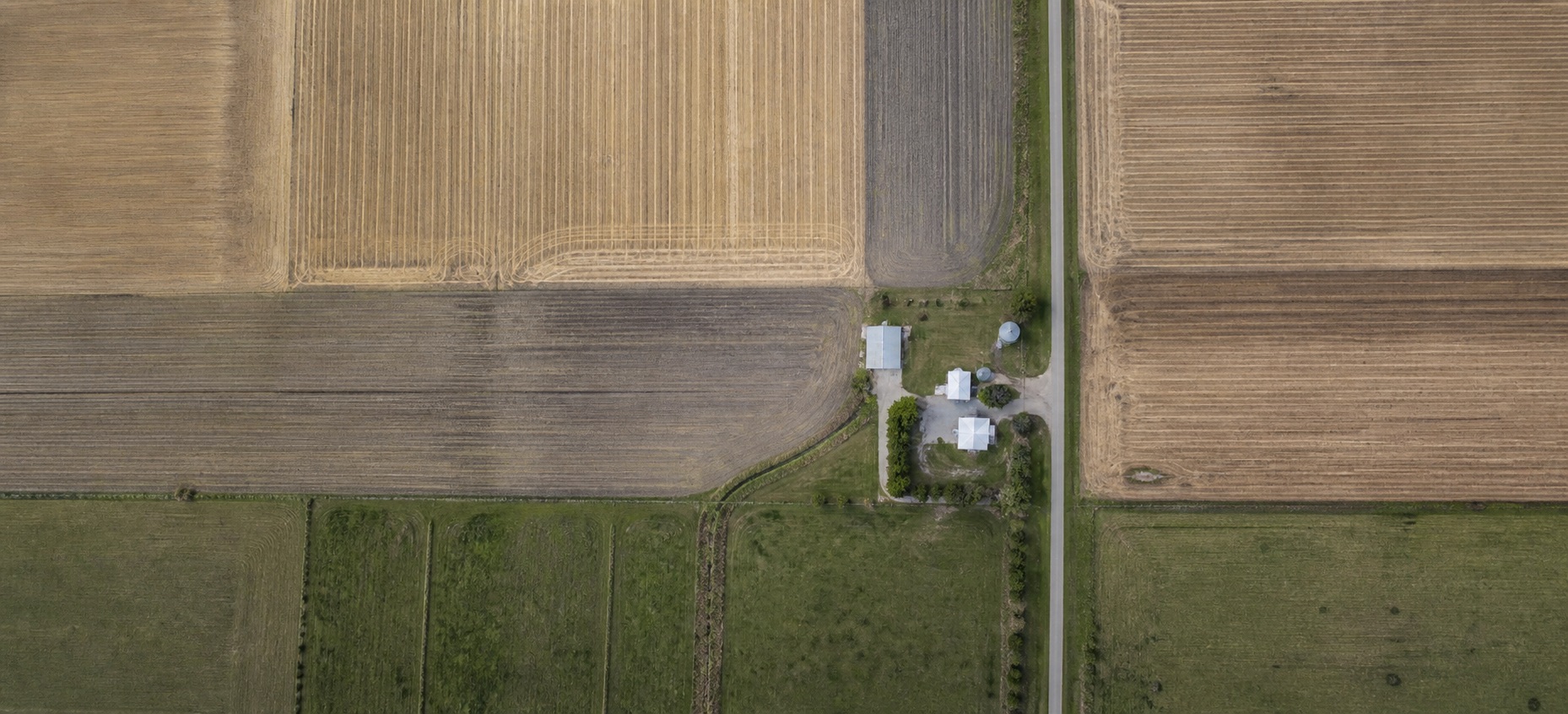 Aerial view of farmland divided into fields, with a small cluster of farm buildings at the centre